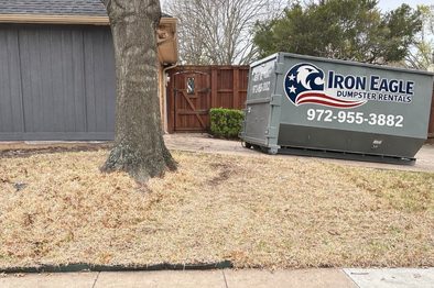 Roll-off dumpster in front of a brick home in Denton County